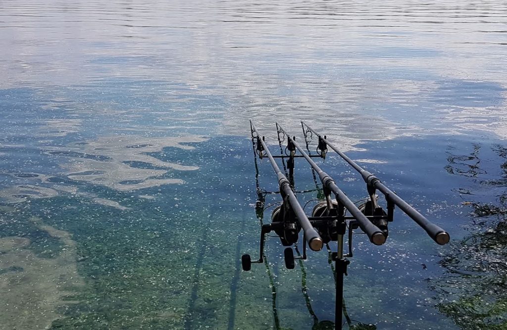 Three carp rods cast out over the clear water at Tar Farm Lake 8, Linear Fisheries, Oxfordshire