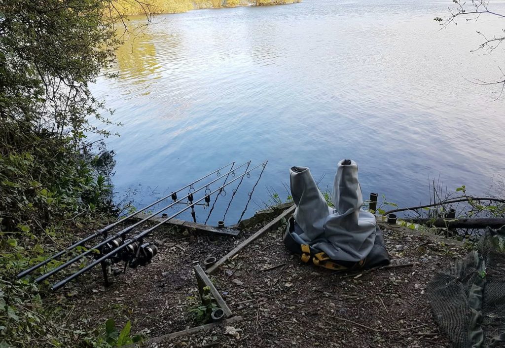 Carp fishing rods on a wooden platform at Big Hayes, Todber Manor, overlooking the lake in Dorset