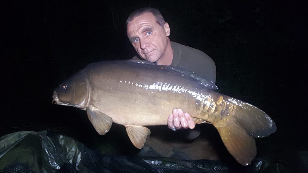 Angler holding a large mirror carp caught during a night session at Broadlands Lake, Calmore, Hampshire
