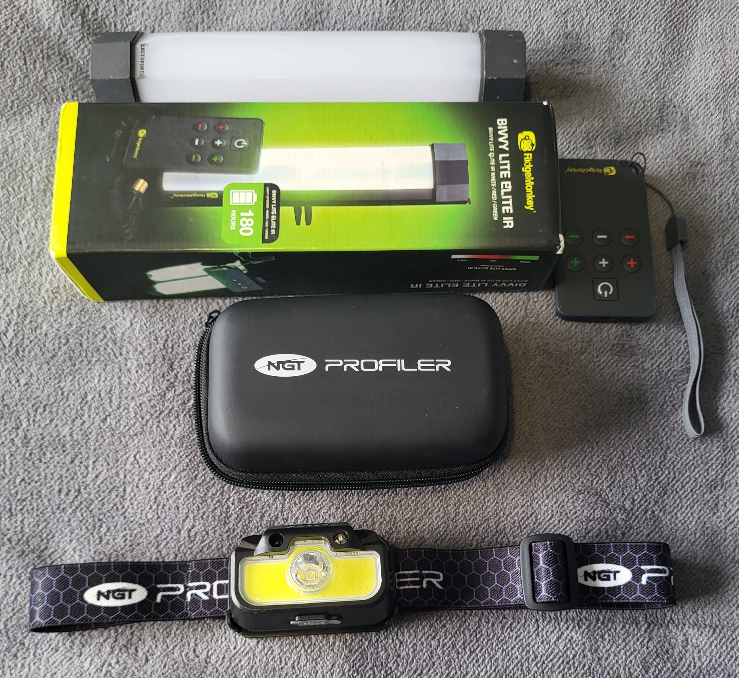 Flat lay of winter carp fishing lighting gear including a RidgeMonkey bivvy light with remote, an NGT Profiler storage case, and an NGT headtorch.